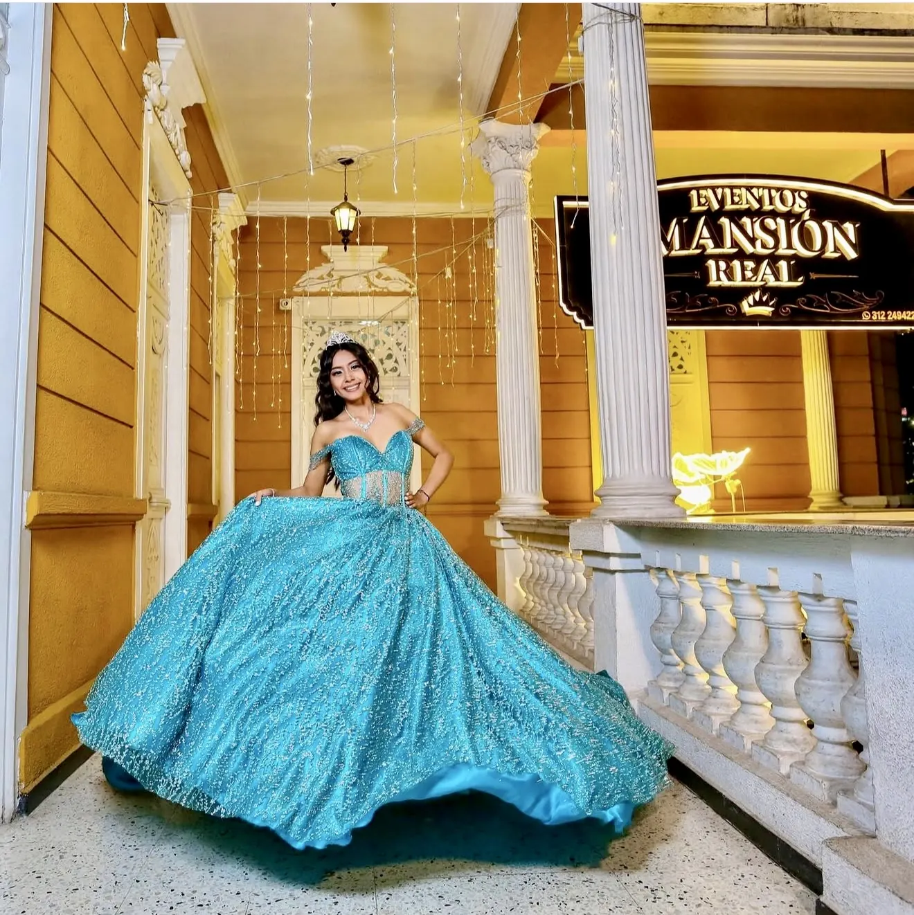 Quinceañera en el balcón medieval bajo el letrero de Mansión Real